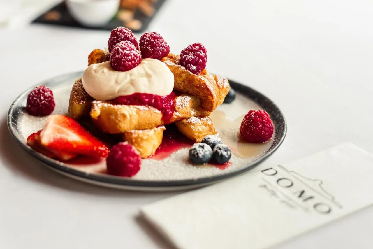 a plate of waffles with berries and whipped cream at Domo Boutique Hotel Birmingham in Birmingham